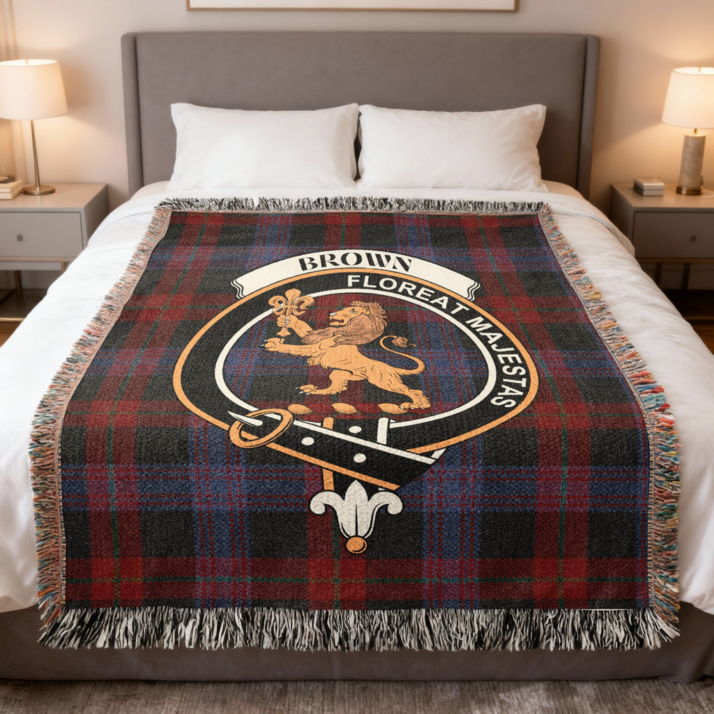 Brown clan crest tartan woven blanket with lion and Floreat Majestas motto on a bed