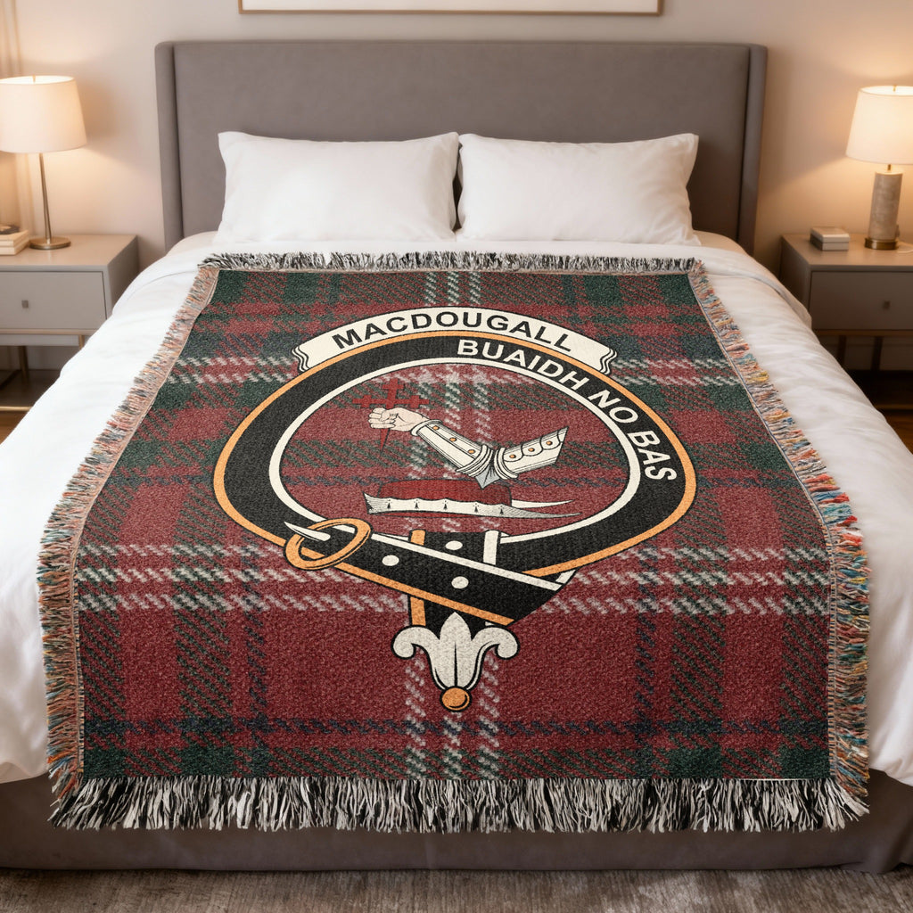 MacDougall woven blanket displayed on a bed, with an armoured arm holding a cross on a red, green and cream tartan background
