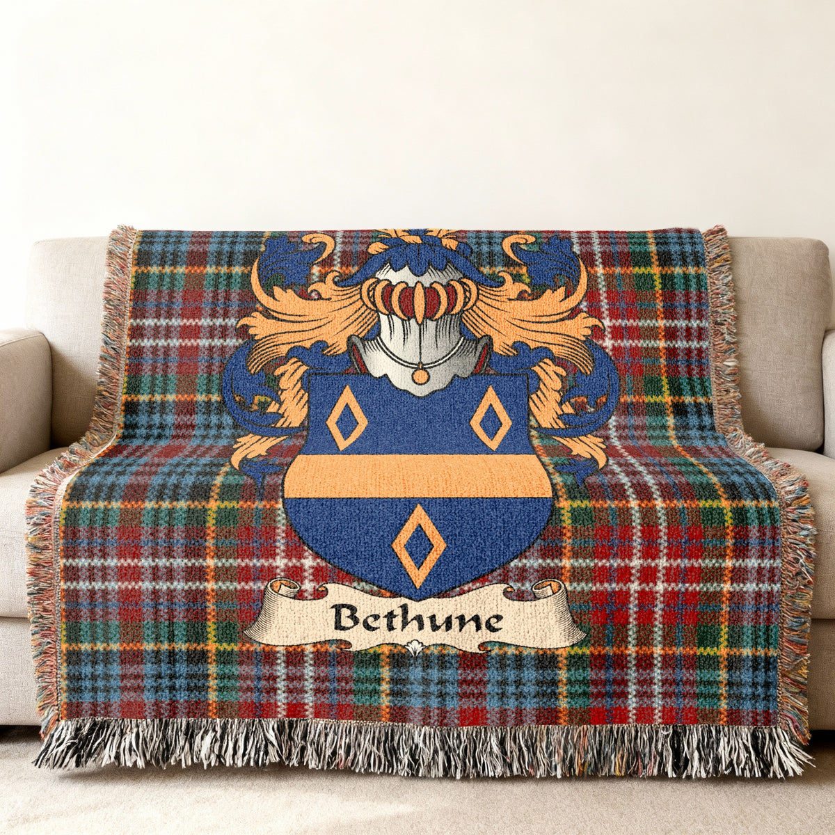 Bethune Scottish family shield woven blanket with Caledonia tartan background on a sofa