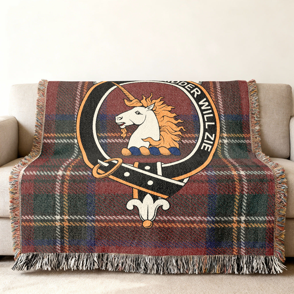Close view of the Stewart of Appin woven blanket draped over a sofa, showing the crest and fringed edges