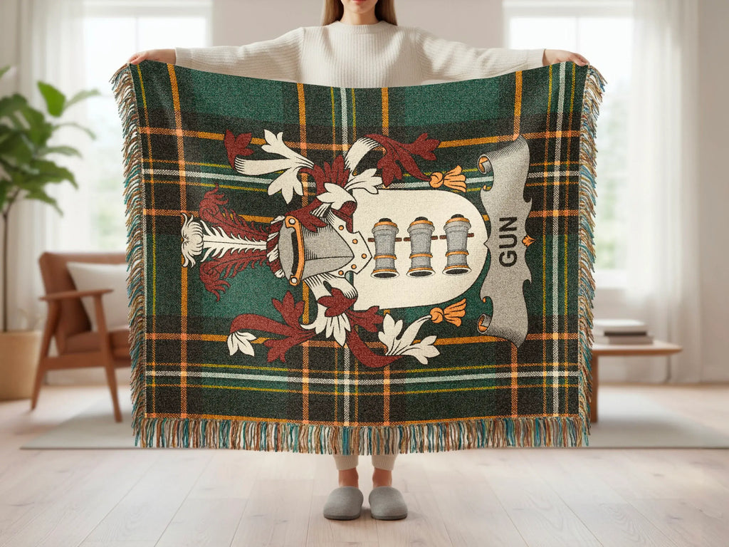Green plaid blanket with a coat of arms featuring three cannons and the word "GUN".
