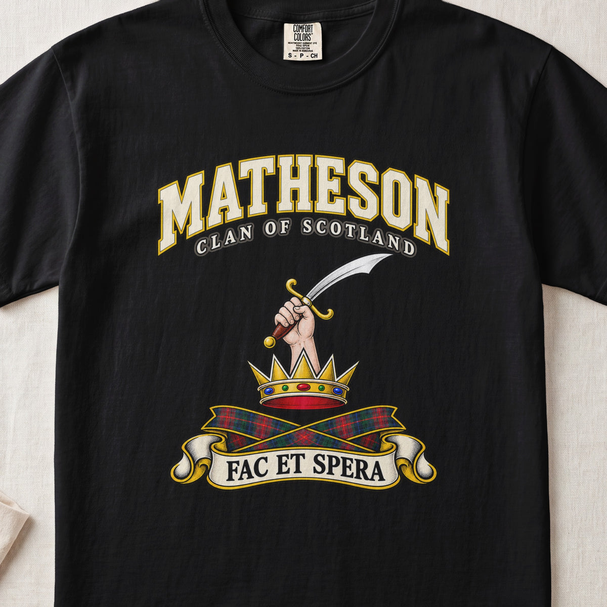 Matheson Scottish clan T-shirt in Black, front view with a hand holding a curved sword above a gold crown and motto banner.