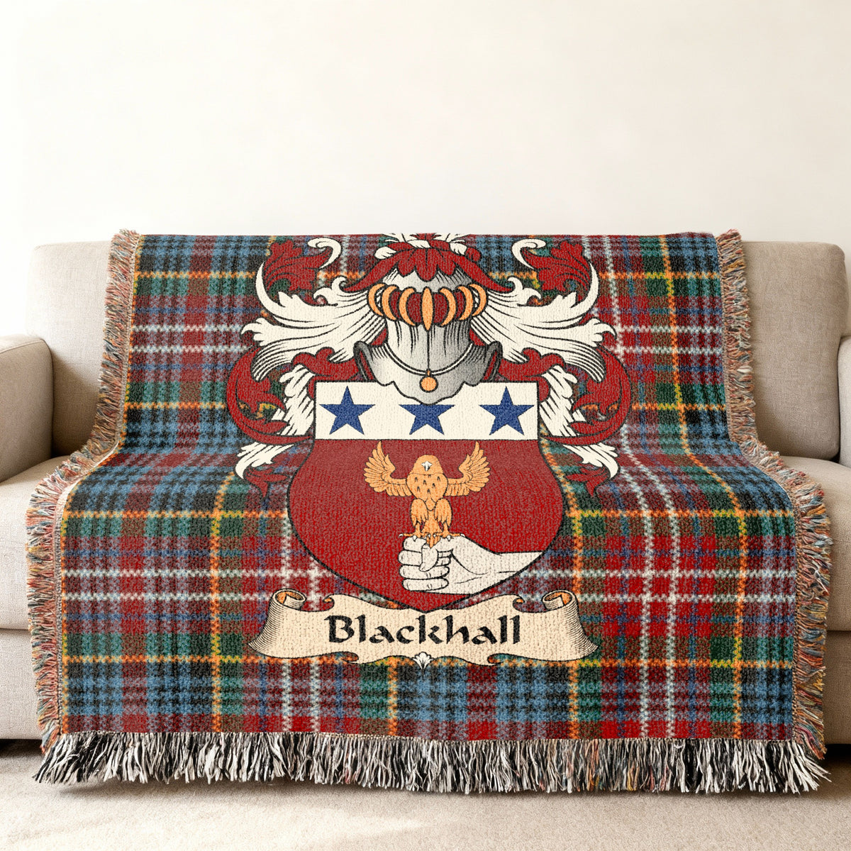 Blackhall Scottish family shield woven blanket with Caledonia tartan background on a sofa