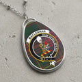 Pendant with MacLennan clan crest and tartan, against a gray textured surface.