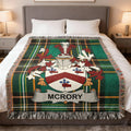 McRory family crest on a green tartan woven blanket on a bed.
