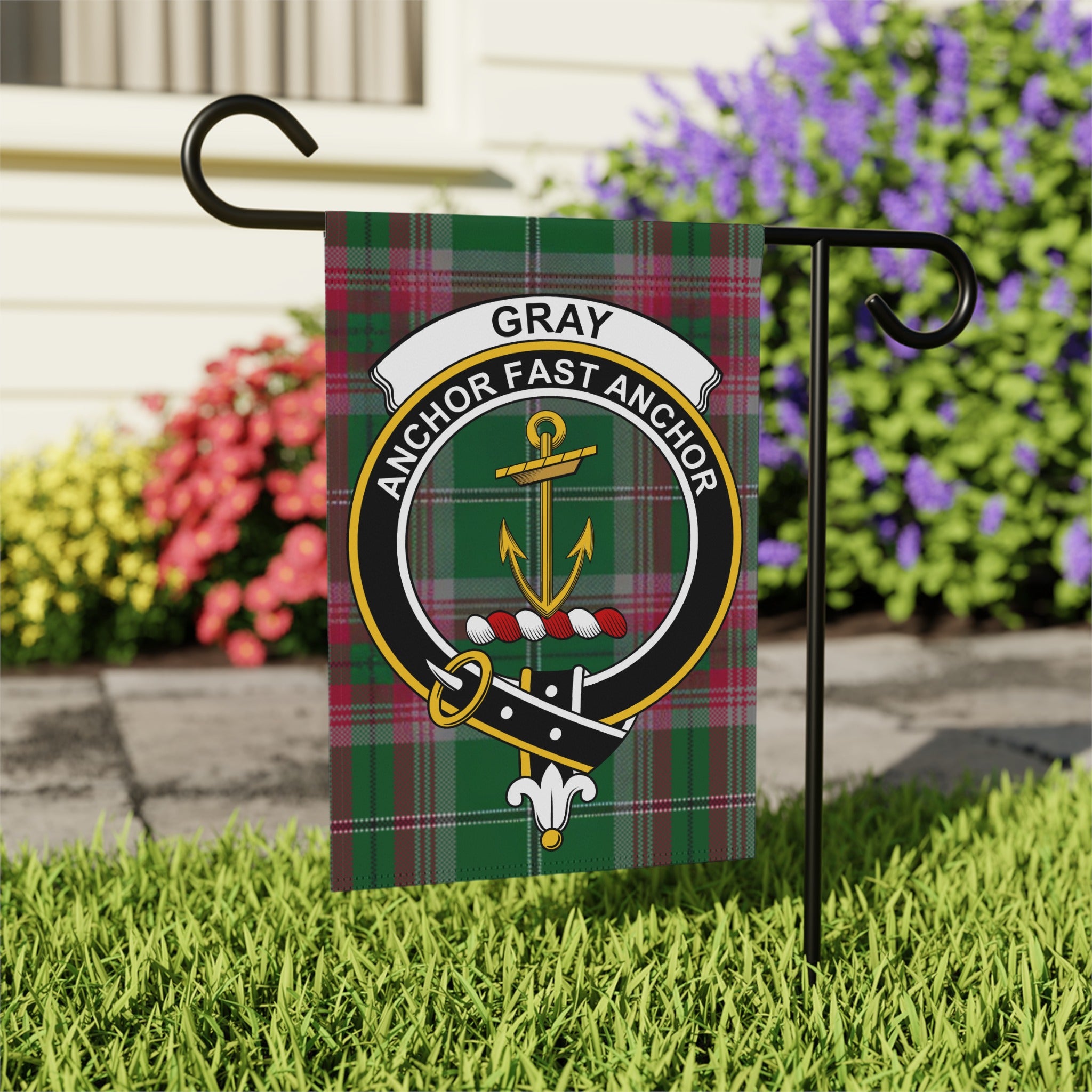 Gray clan crest with motto on tartan garden flag — close-up