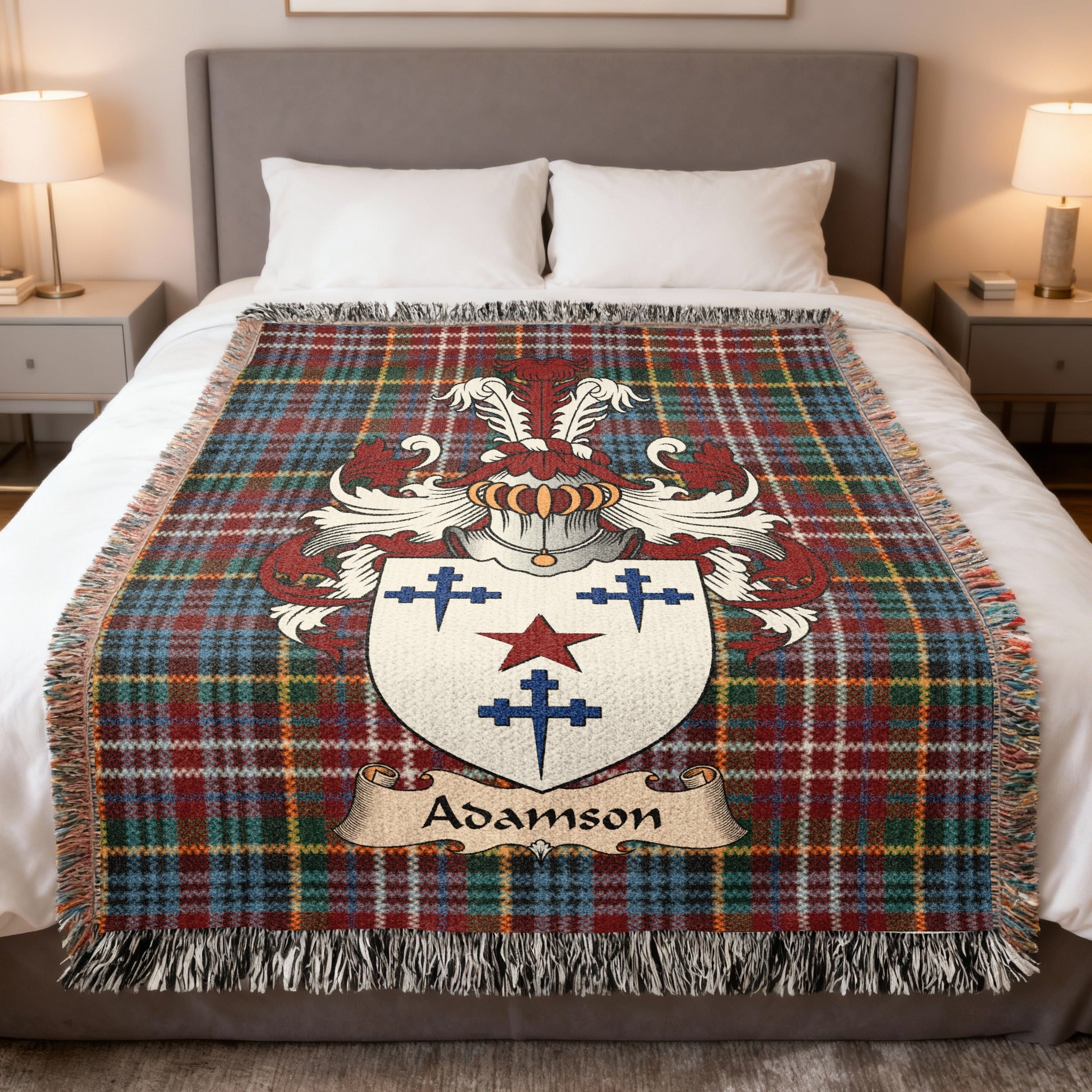 Adamson Scottish family crest woven blanket on a Caledonia tartan background, displayed on a bed