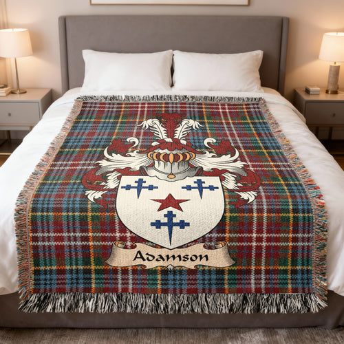 Adamson Scottish family crest woven blanket on a Caledonia tartan background, displayed on a bed