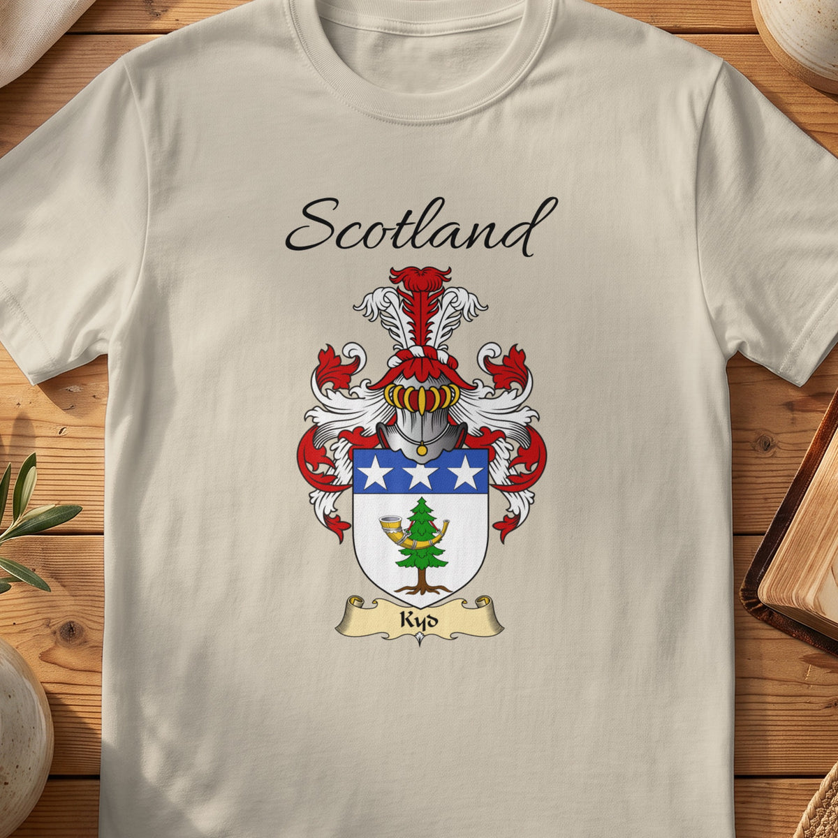 Sand Kyd Scottish family shield T-shirt featuring a blue top band with white stars above a green motif