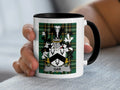 White mug with black handle featuring a green plaid background and a coat of arms with "GAR" text.
