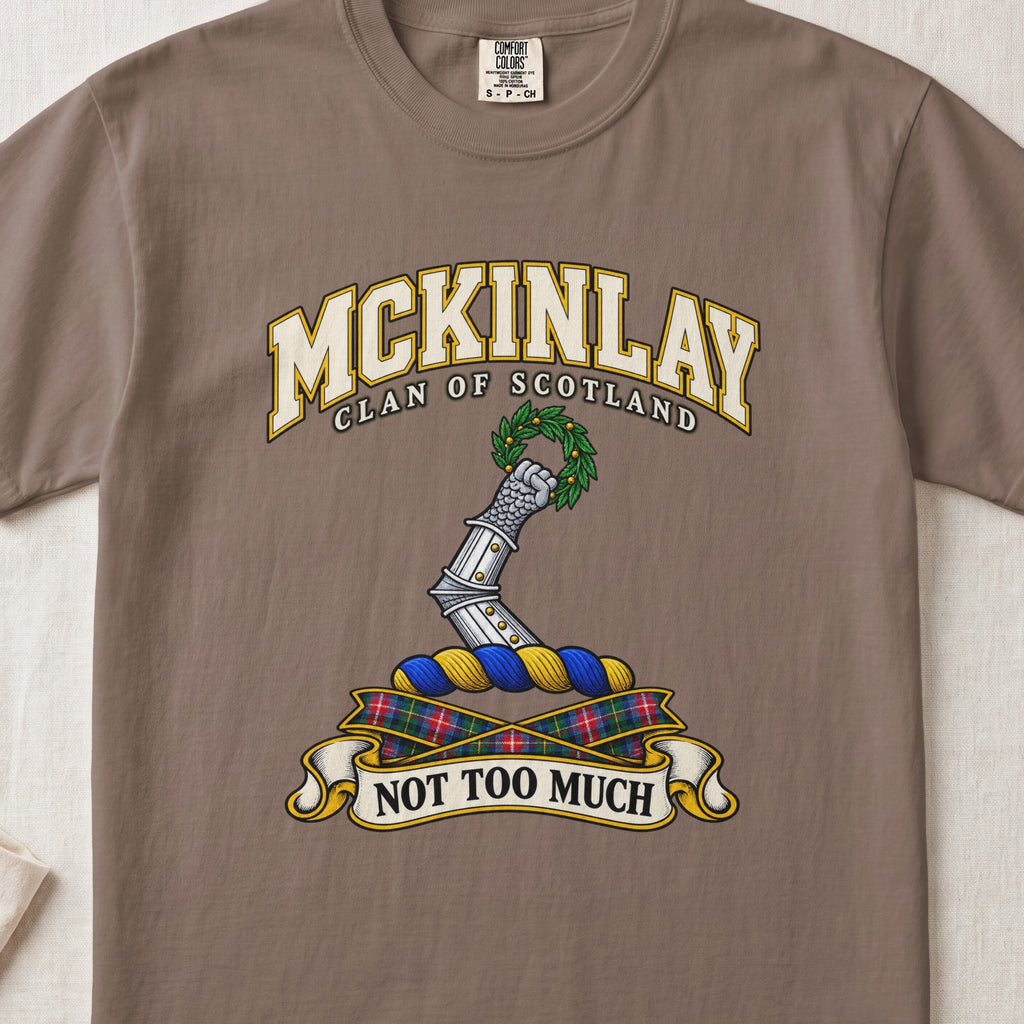 McKinlay Scottish clan T-shirt in Espresso, front view with an armored arm holding a green leafy wreath and motto banner.