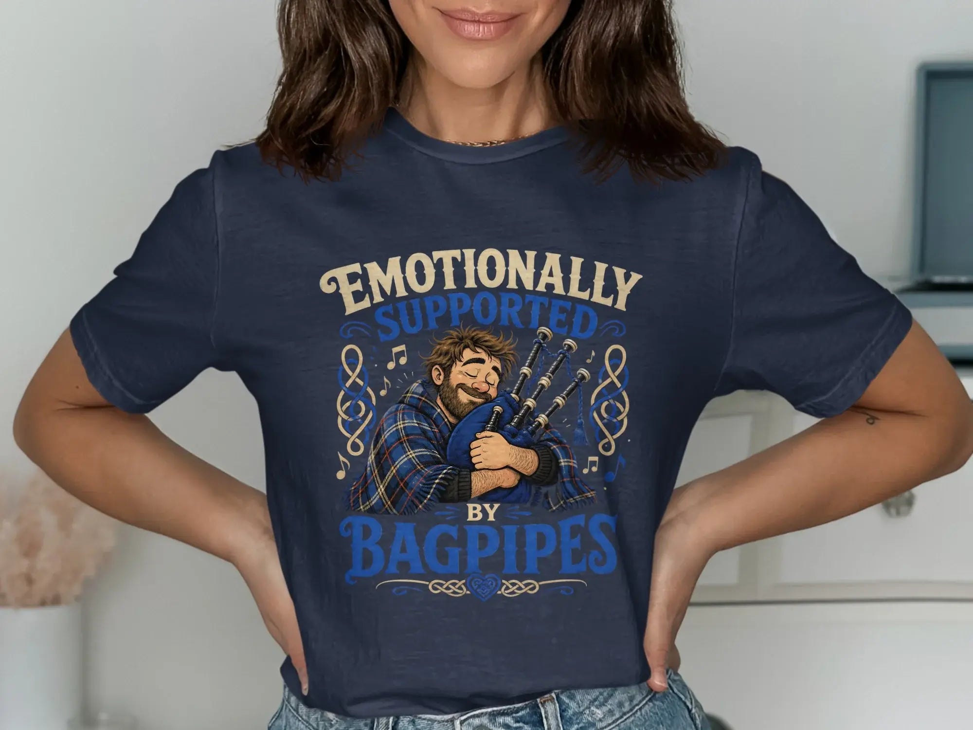 Dark blue t-shirt with "Emotionally Supported by Bagpipes" text and bagpiper illustration.