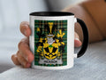 White mug with black rim, featuring Hickson family crest on plaid background.