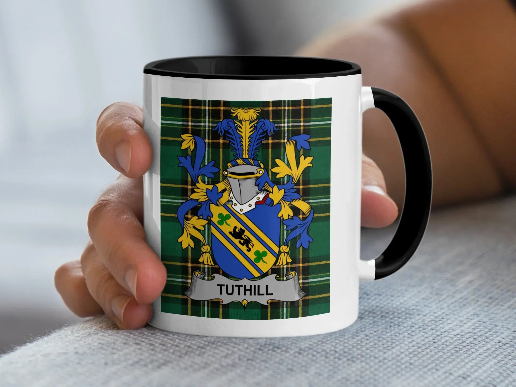 White mug with black handle displaying Tuthill family crest on plaid background.