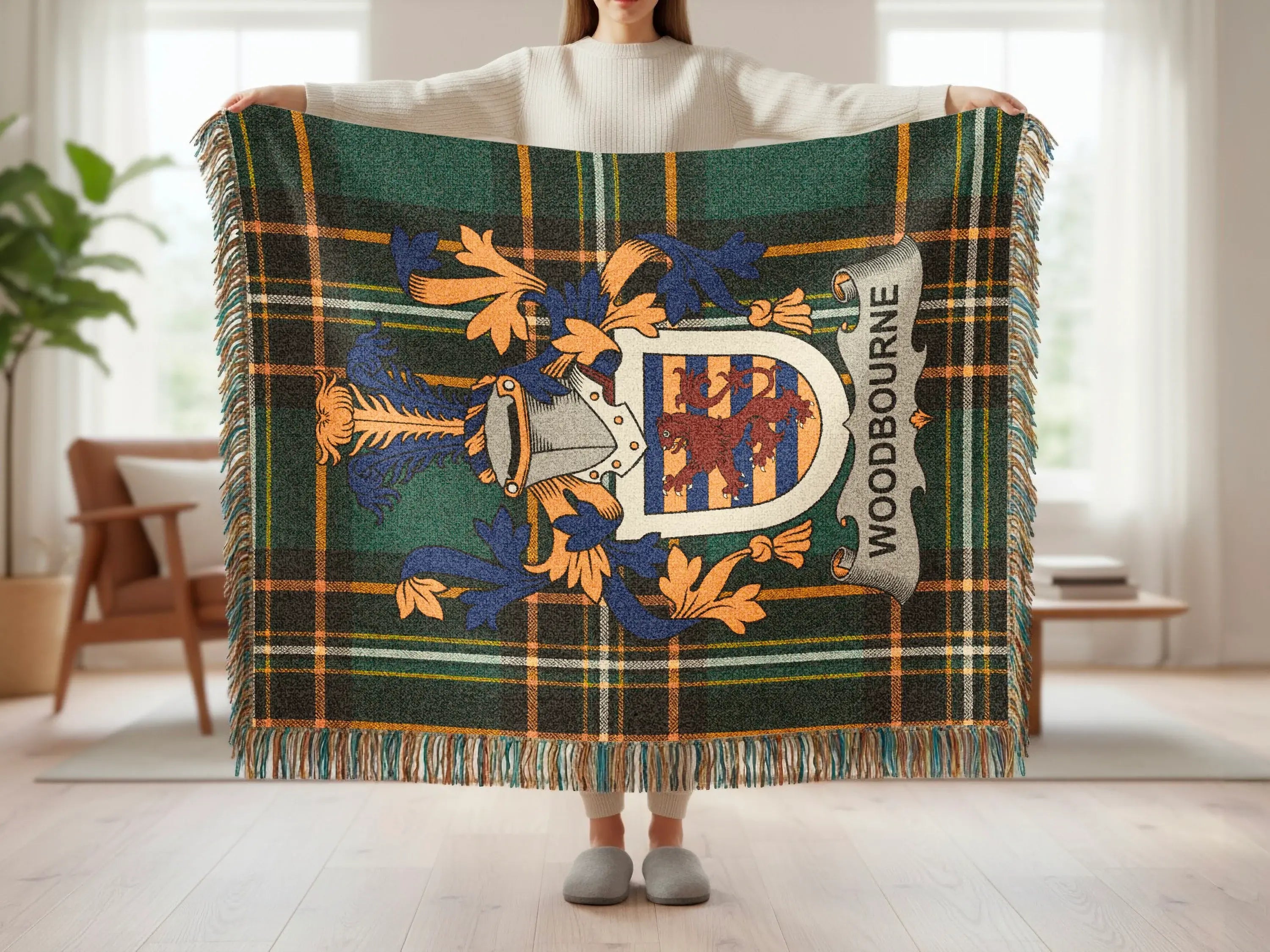 Green and blue plaid throw blanket with Woodbourne crest held up by a person.