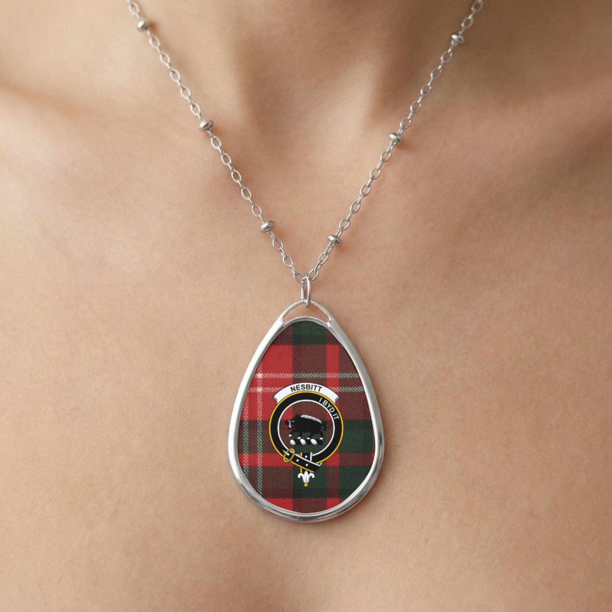 Oval pendant with red and green plaid and Nesbitt crest on a silver chain.