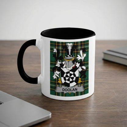 White mug with black rim featuring the DOOLAN family crest on a plaid background.