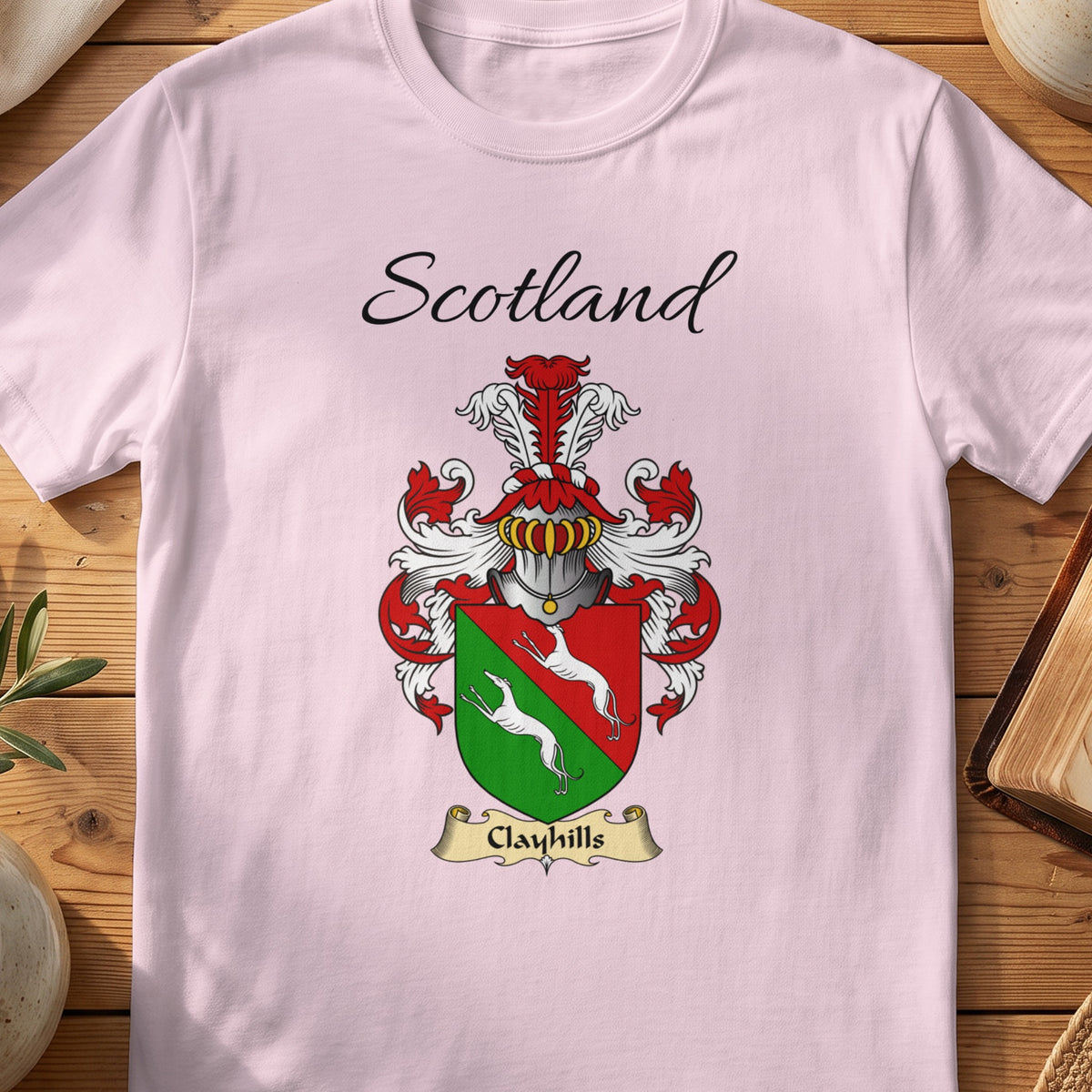 Light Pink Clayhills Scottish family shield T-shirt featuring white animals on a red-and-green shield