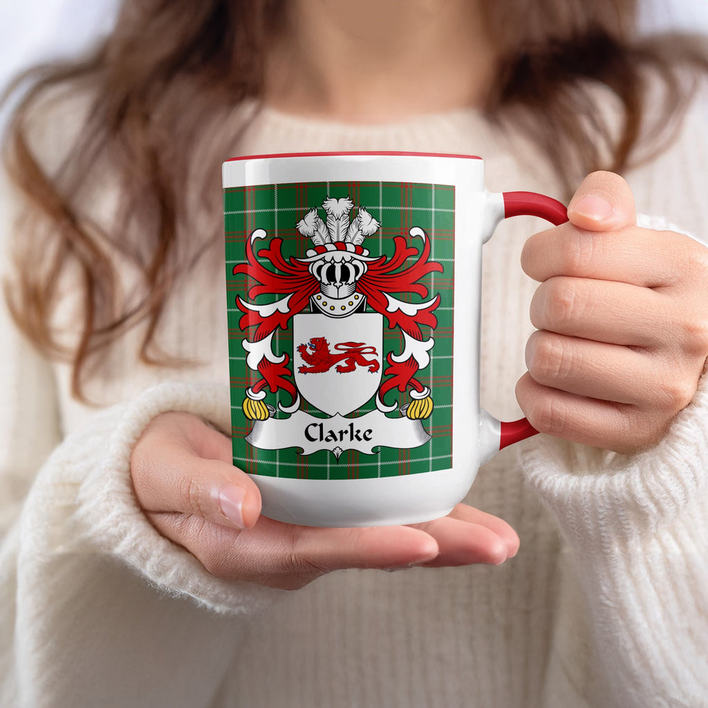 White mug with red handle featuring Clarke family crest on green tartan background.