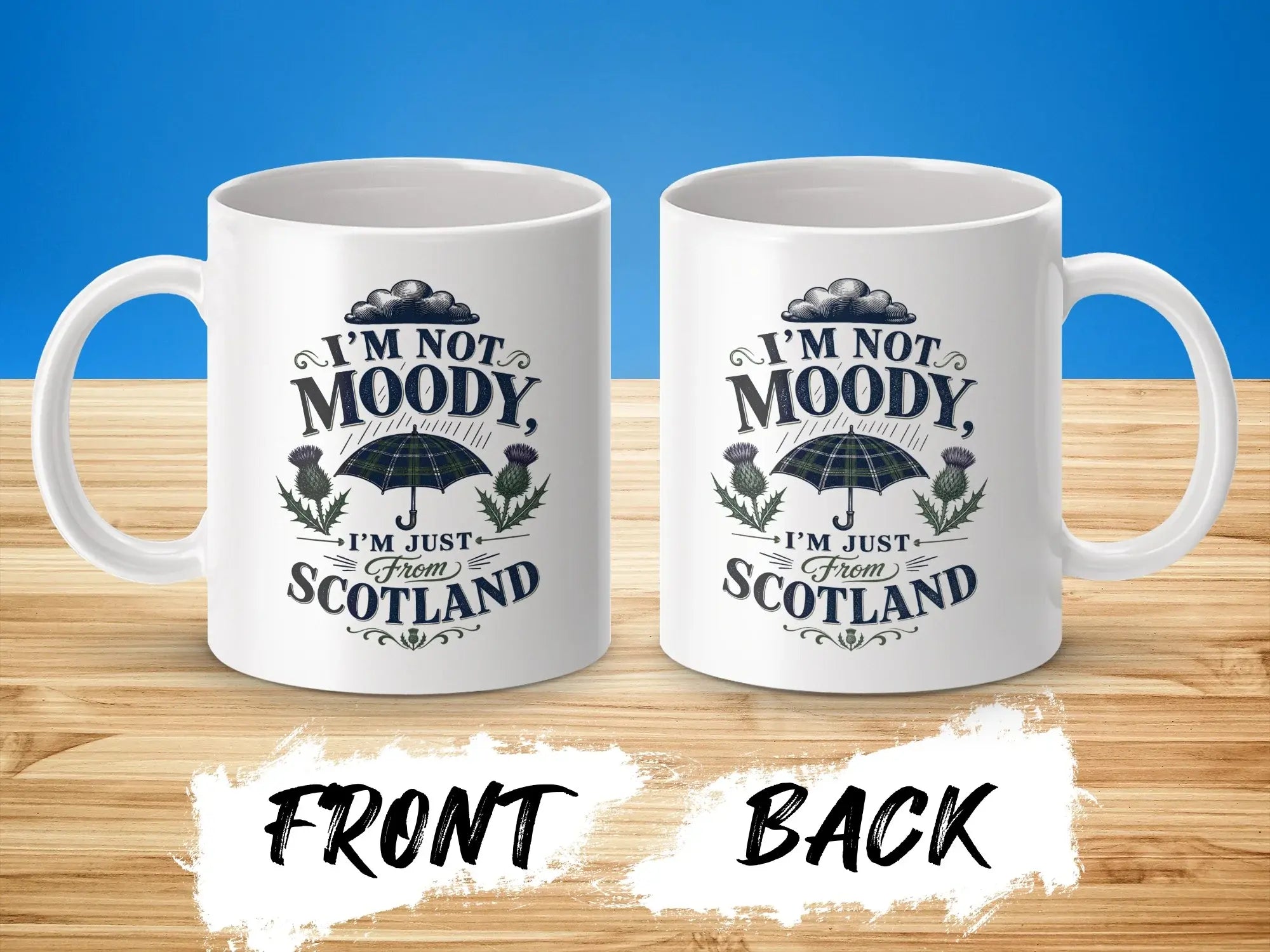 Two white mugs showing "I'm Not Moody, I'm Just From Scotland" design with thistle and umbrella.