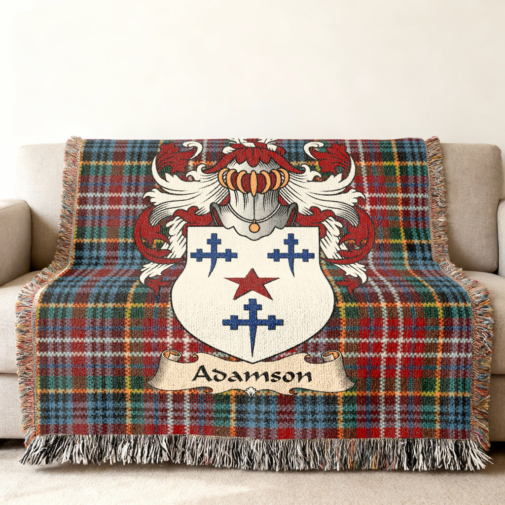 Adamson Scottish family shield woven blanket with Caledonia tartan background on a sofa