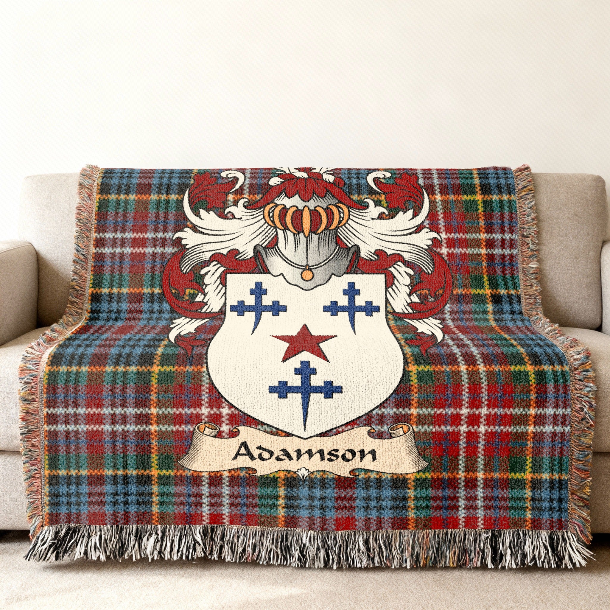 Adamson Scottish family shield woven blanket with Caledonia tartan background on a sofa