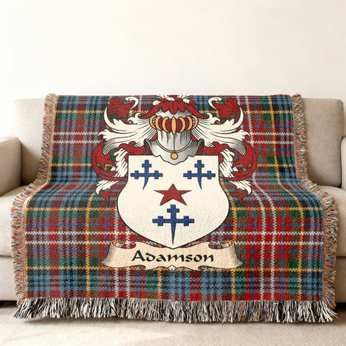 Adamson Scottish family shield woven blanket with Caledonia tartan background on a sofa