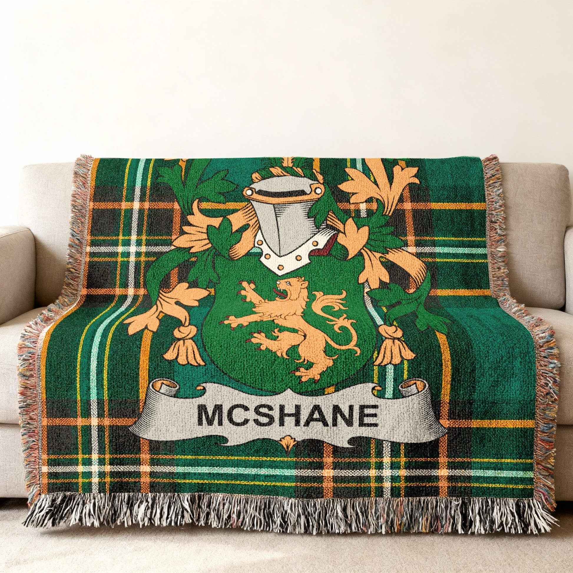 Green tartan blanket with McShane family crest on a couch.