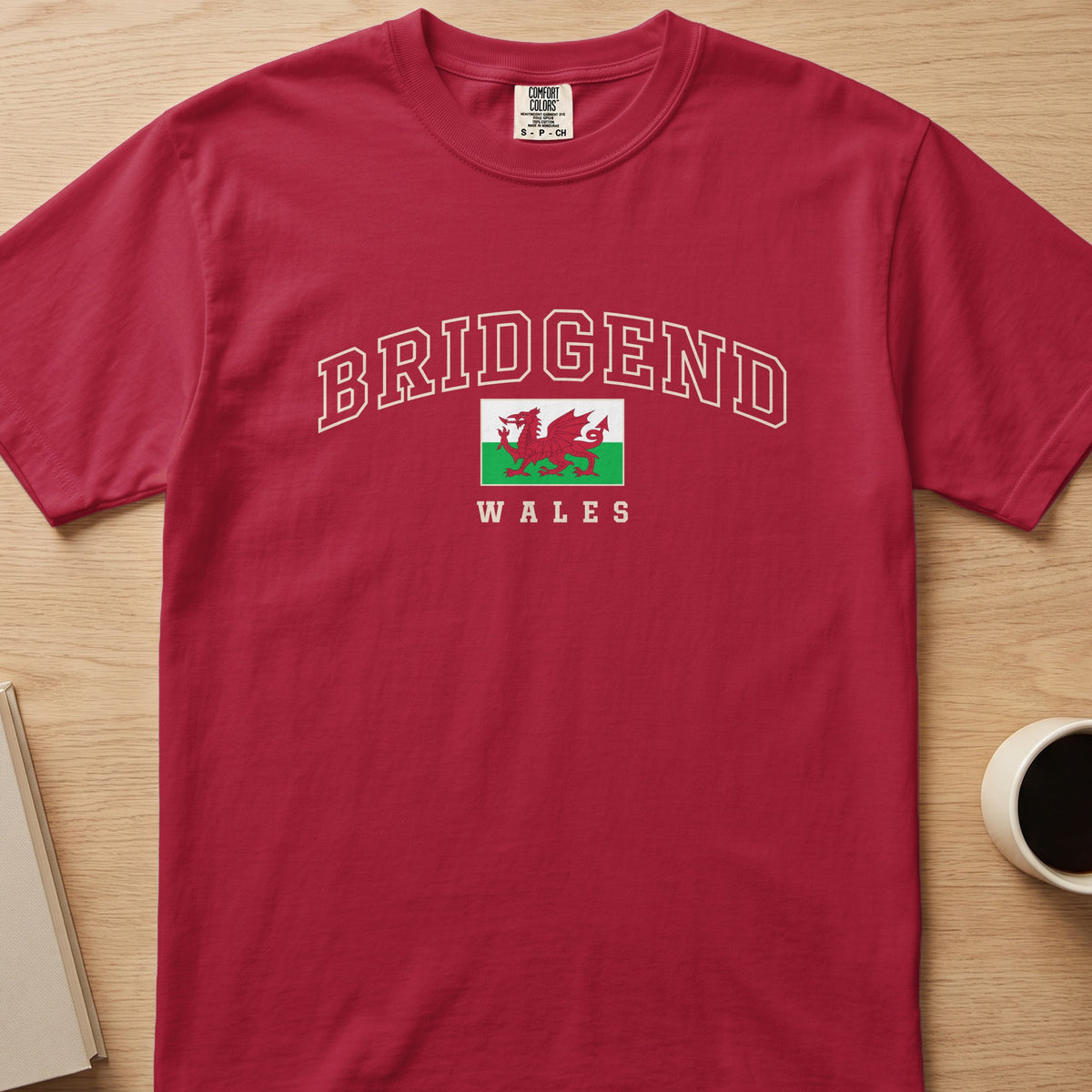 Red Bridgend Wales T-shirt laid flat, with cream collegiate outline lettering and a red Welsh dragon flag.