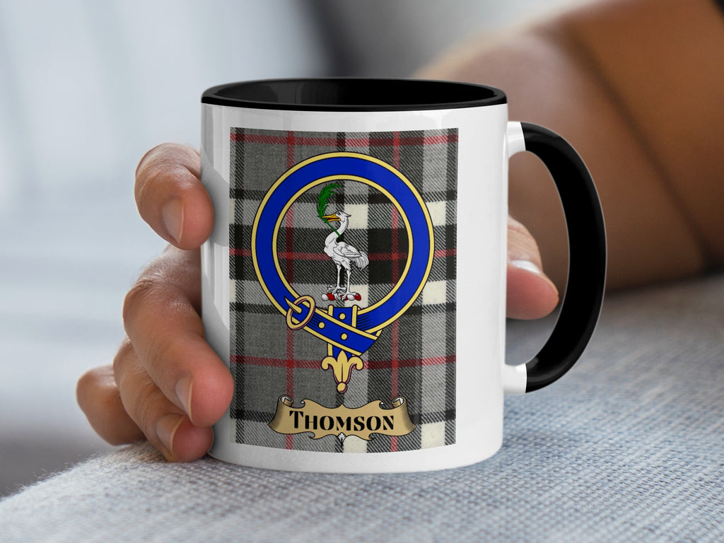 Thomson clan crest coffee mug held in hand — tartan background design