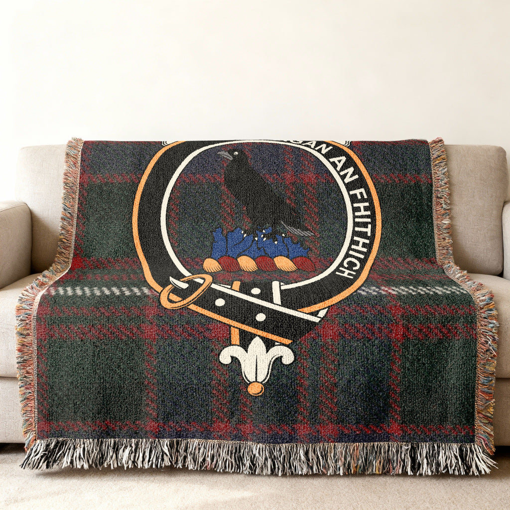 Close view of the MacDonell of Glengarry woven blanket draped over a sofa, showing the crest and fringed edges