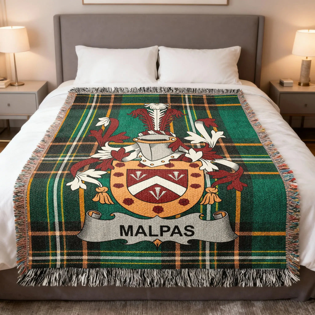 MALPAS crest on a green plaid throw blanket on a bed.
