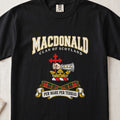 MacDonald graphic T-shirt in Black, front flat lay showing varsity lettering and armoured forearm with hand holding red cross.