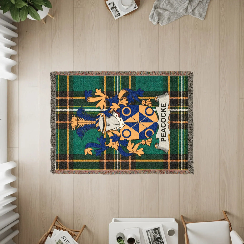 Green plaid woven blanket with PEACOCK crest and gold accents.