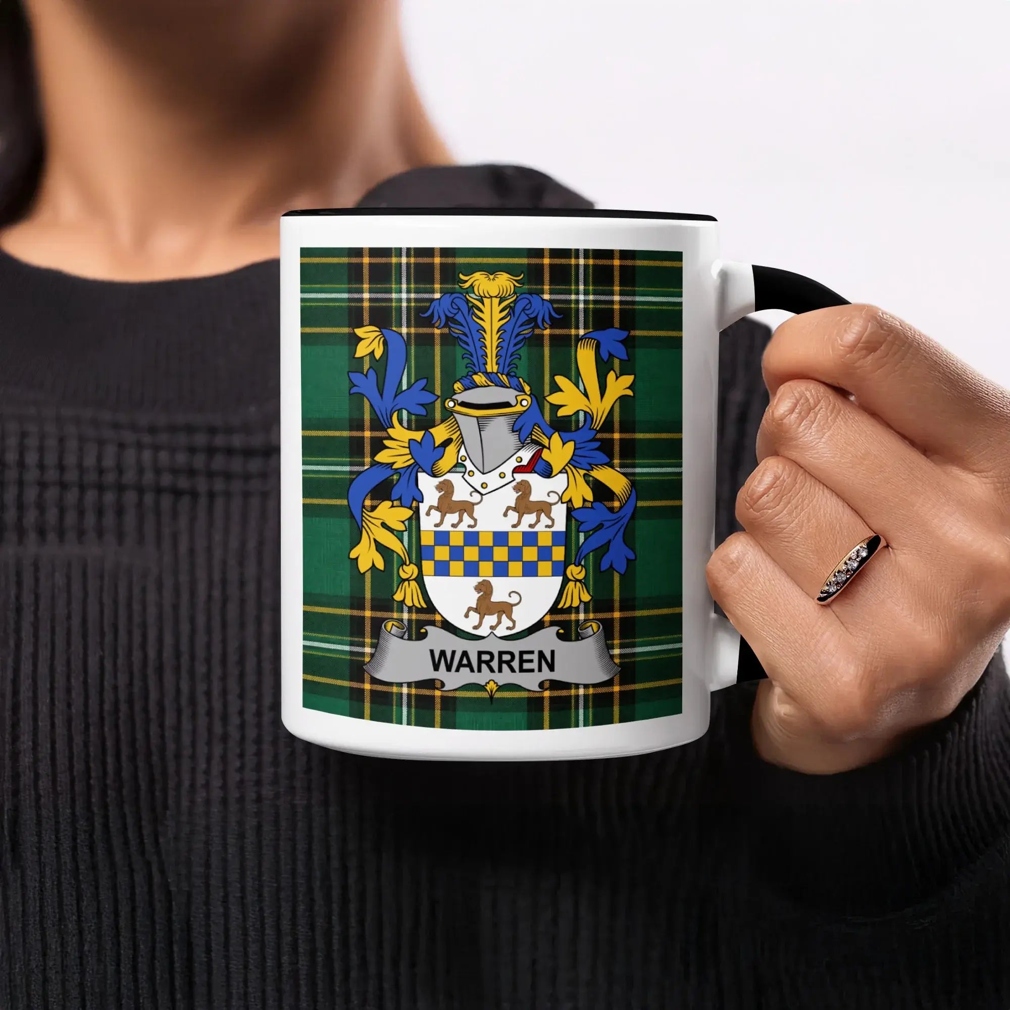 Warren coat of arms on a tartan plaid mug held by a person.