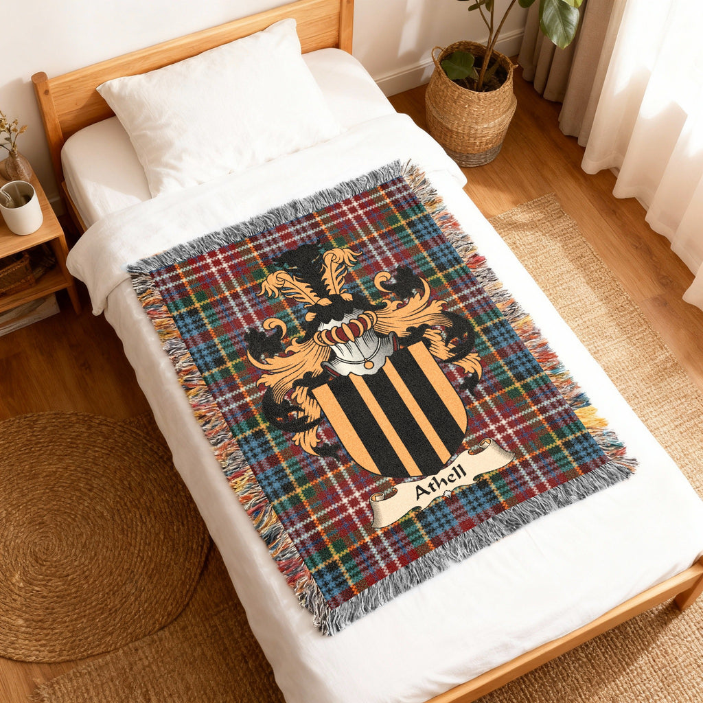 Athell Scottish family shield woven blanket with Caledonia tartan background, displayed on a bed