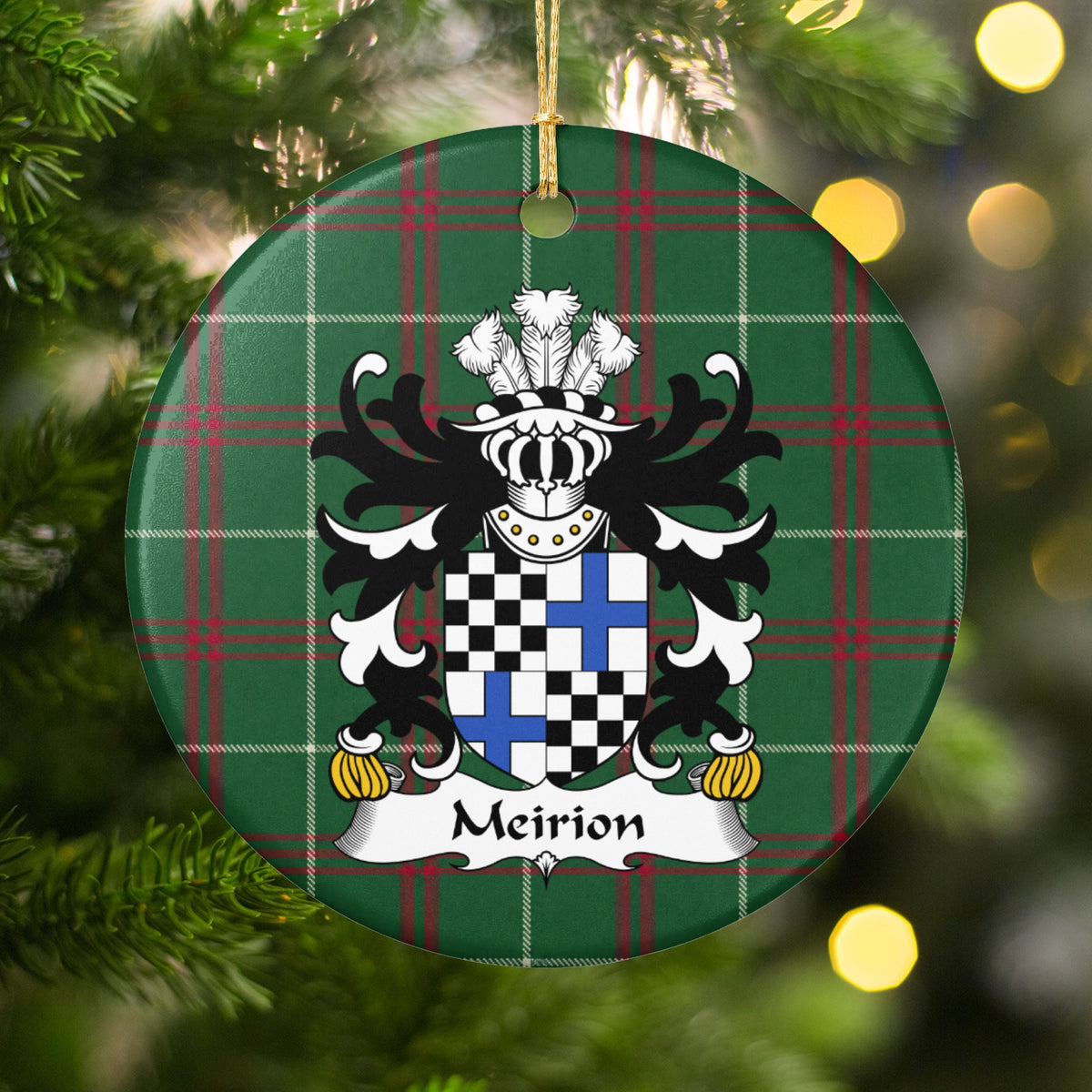 Meirion ornament hanging among Christmas tree branches and warm lights, with a quartered shield with black-and-white checks and blue crosses on Welsh National Tartan.