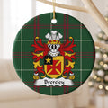 Brereley ornament hanging from a pale wooden branch; a red flared cross on gold with a gold star in a black corner panel on Welsh national tartan.