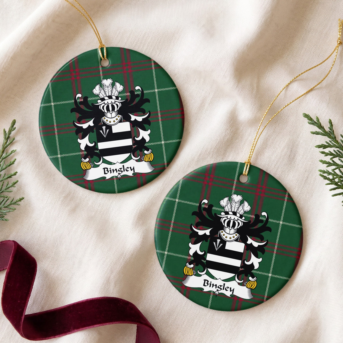 Two Bingley ornaments on cream fabric beside evergreen and burgundy ribbon; two black bars on white with a white arrowhead in a black corner panel on Welsh national tartan.