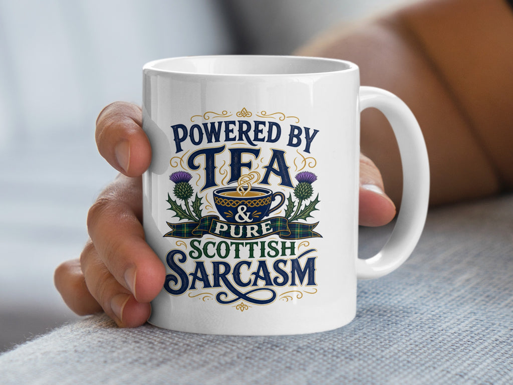 White mug with text "Powered by Tea & Pure Scottish Sarcasm" and thistle graphic.