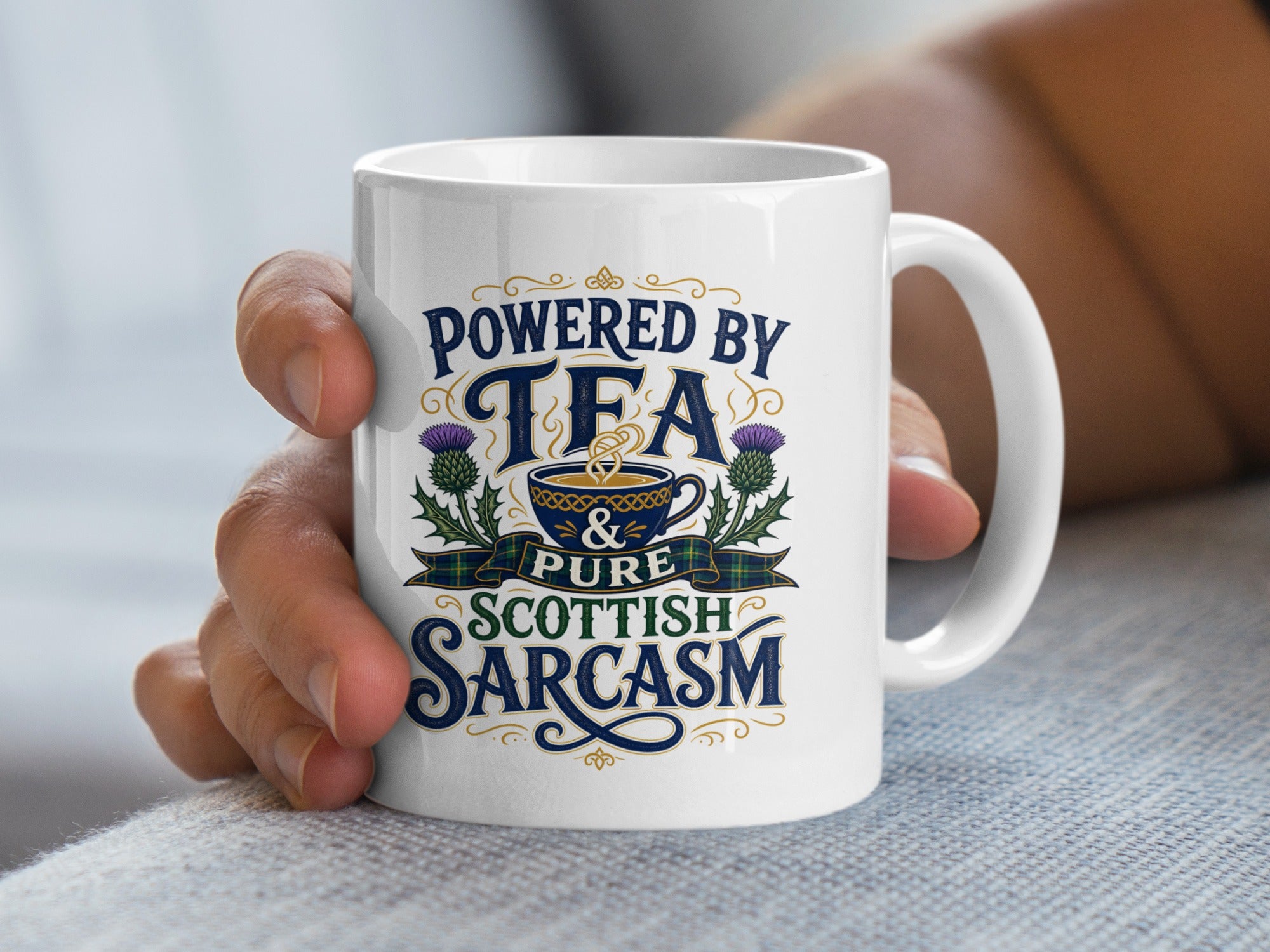 White mug with text "Powered by Tea & Pure Scottish Sarcasm" and thistle graphic.
