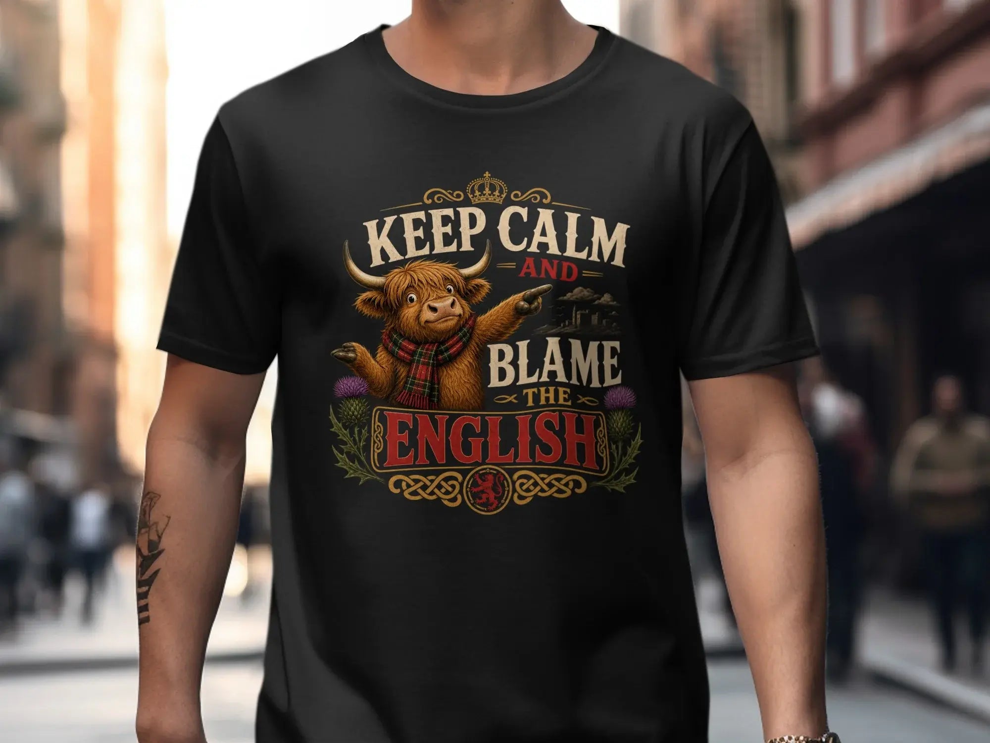 Black t-shirt with "Keep Calm and Blame the English" and Highland cow graphic.