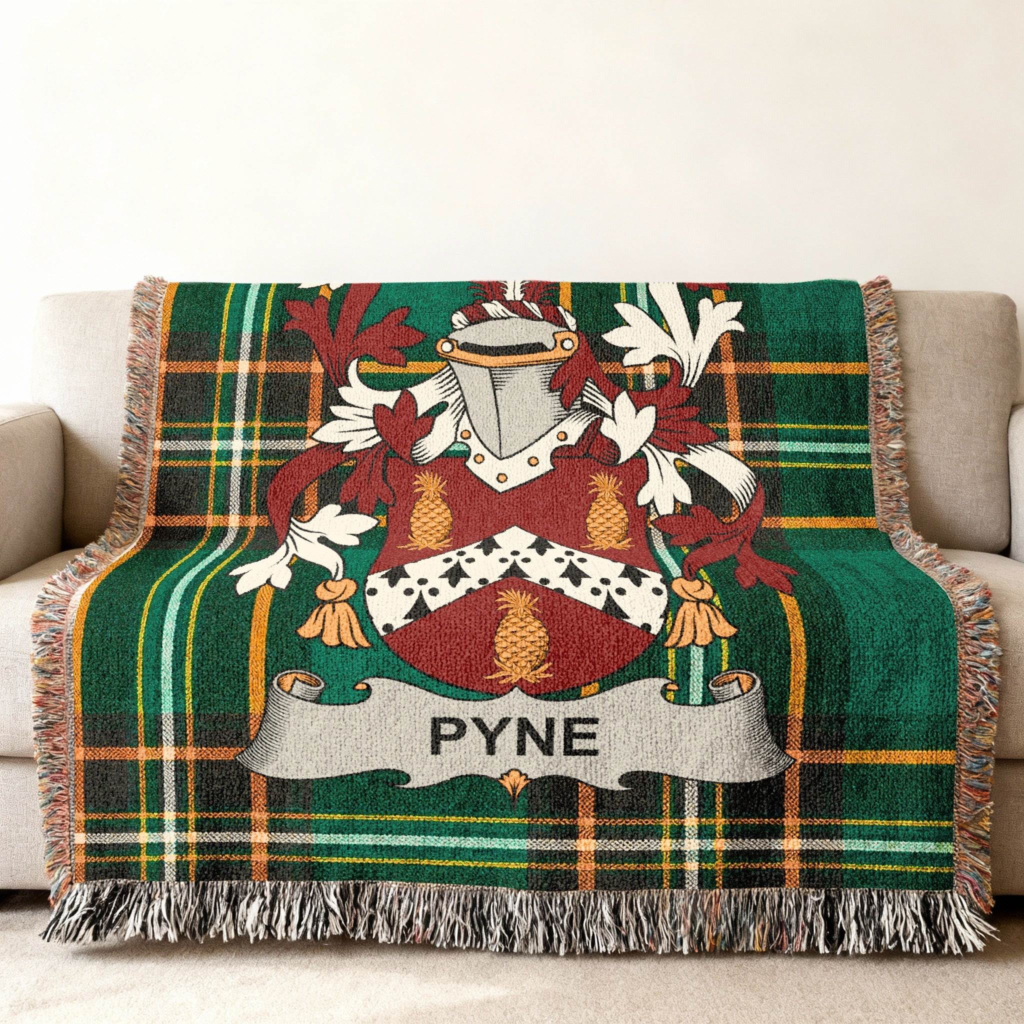 Green plaid throw blanket with Pyne family crest centered on top.