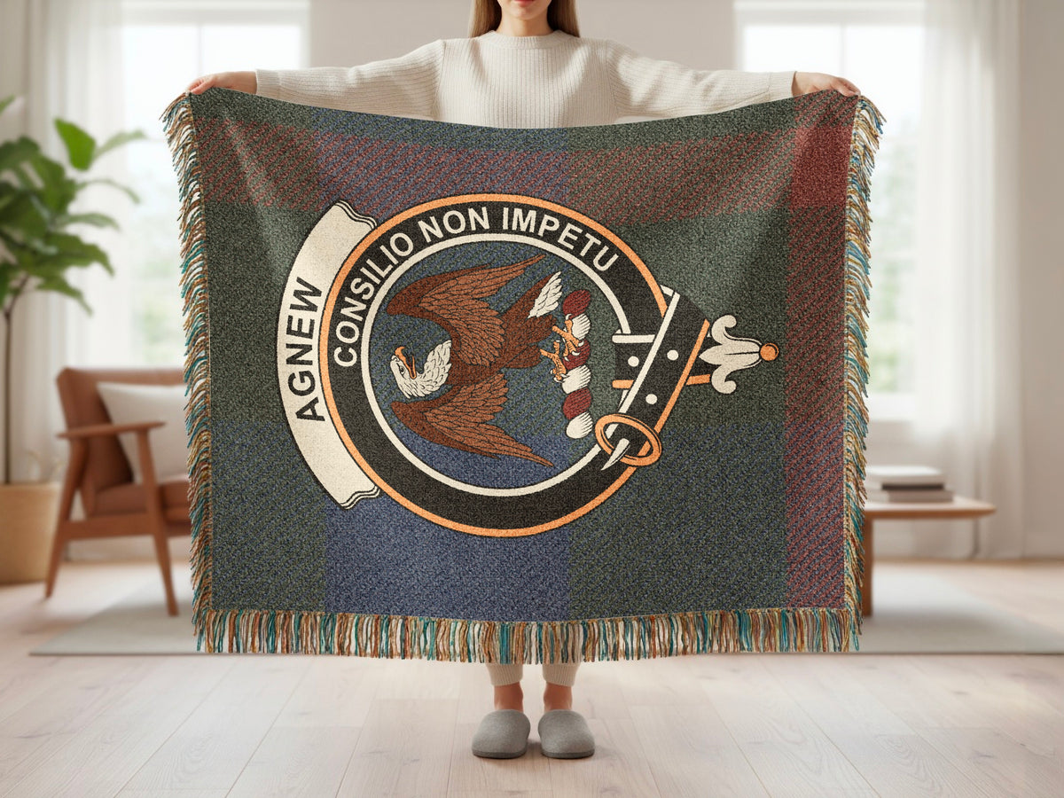 Person holding the Agnew woven blanket to show the full design, tartan background and fringe