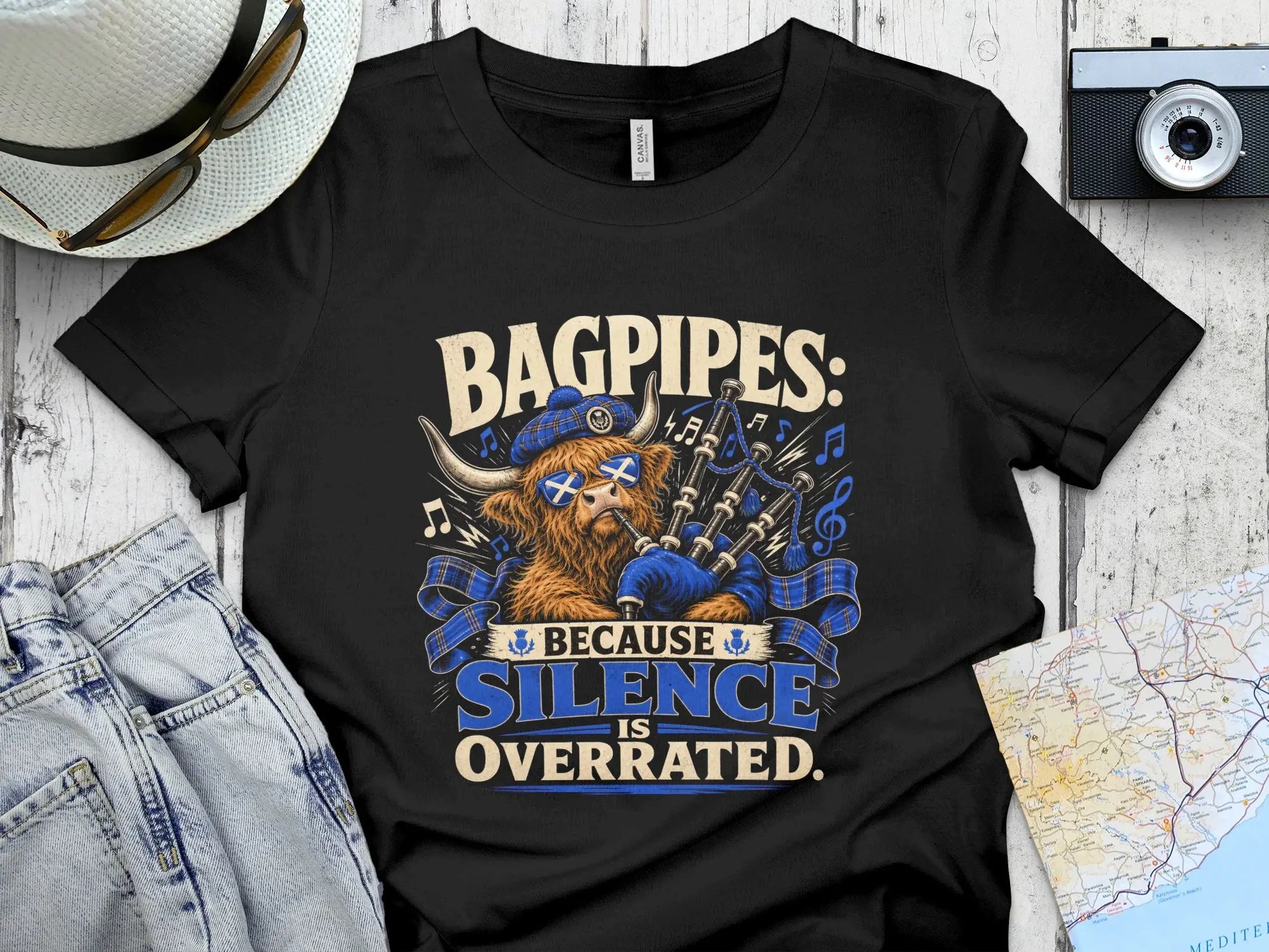 Black t-shirt with graphic of a Highland cow playing bagpipes and text "BAGPIPES: BECAUSE SILENCE IS OVERRATED."