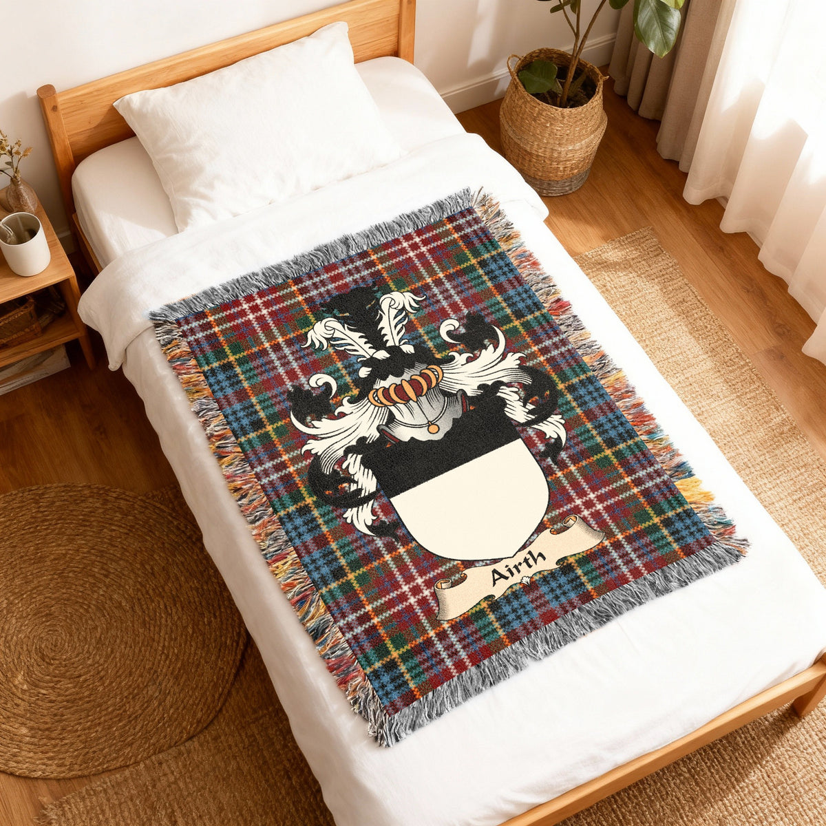 Airth Scottish family shield woven blanket with Caledonia tartan background, displayed on a bed