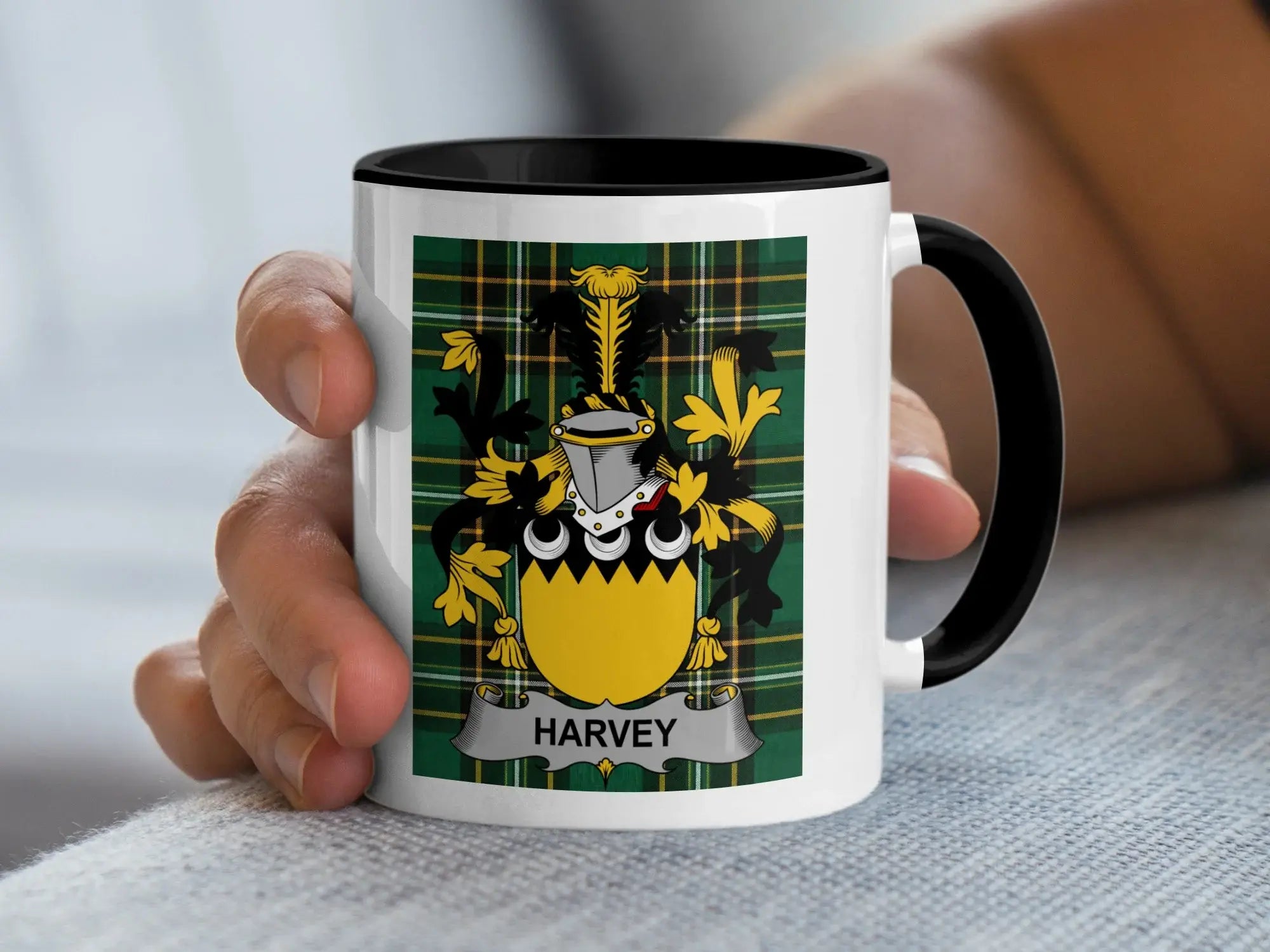 White mug with black rim featuring a green tartan plaid design and a family crest.