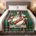 Veile family crest on a green plaid throw blanket on a bed.