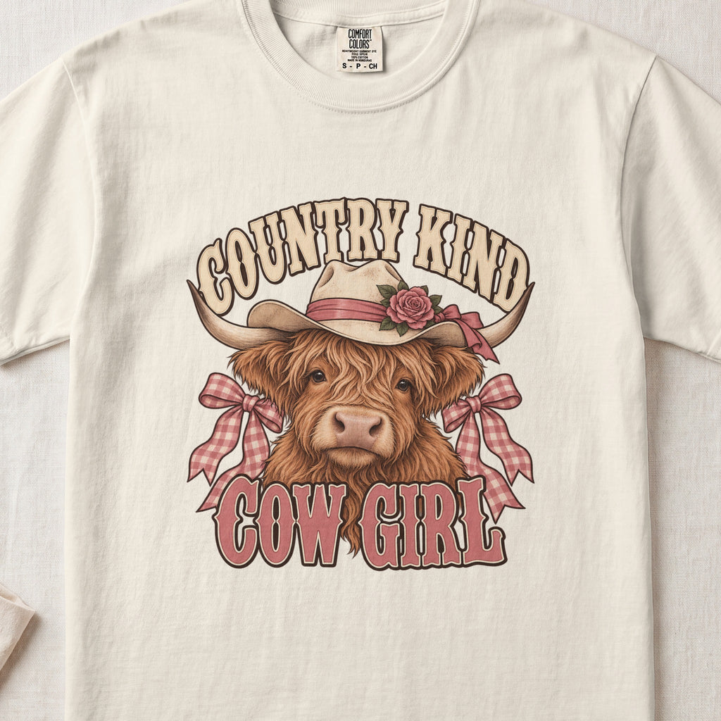 Country Kind Cow Girl Highland cow design on an Ivory Comfort Colors 1717 T-shirt, flat lay