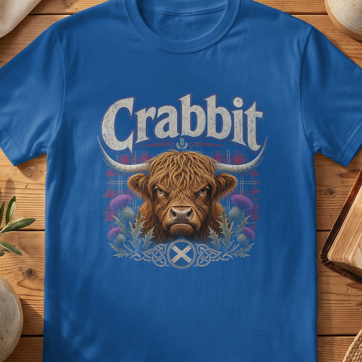 Blue t-shirt with "Crabbit" text, Highland cow, thistles, and Scottish flag.